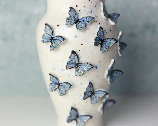 Decorative vase with blue butterfly decals on a blurred background