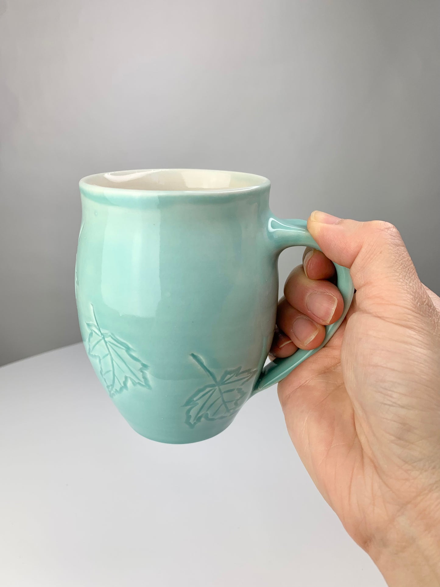 12 oz porcelain mug with carved maple leaf design in turquoise