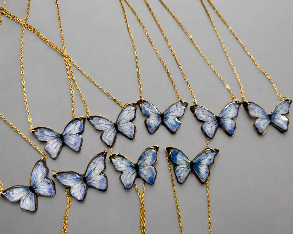 Butterfly necklaces on gold chains displayed against a light background