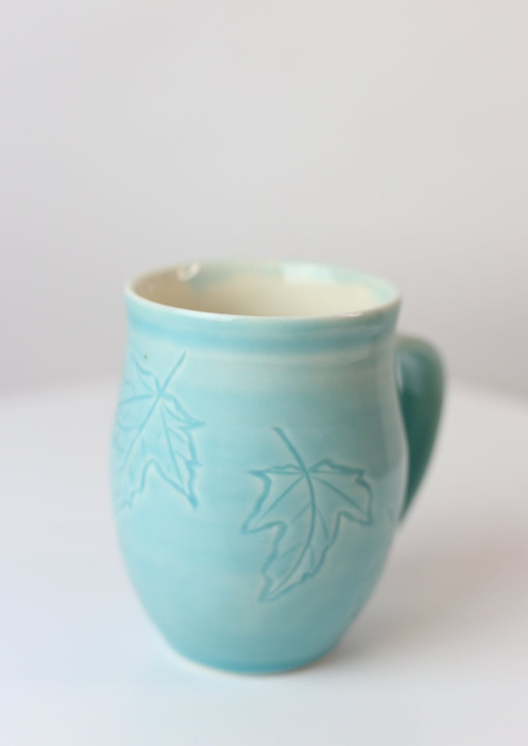 12 oz porcelain mug with carved maple leaf design in turquoise