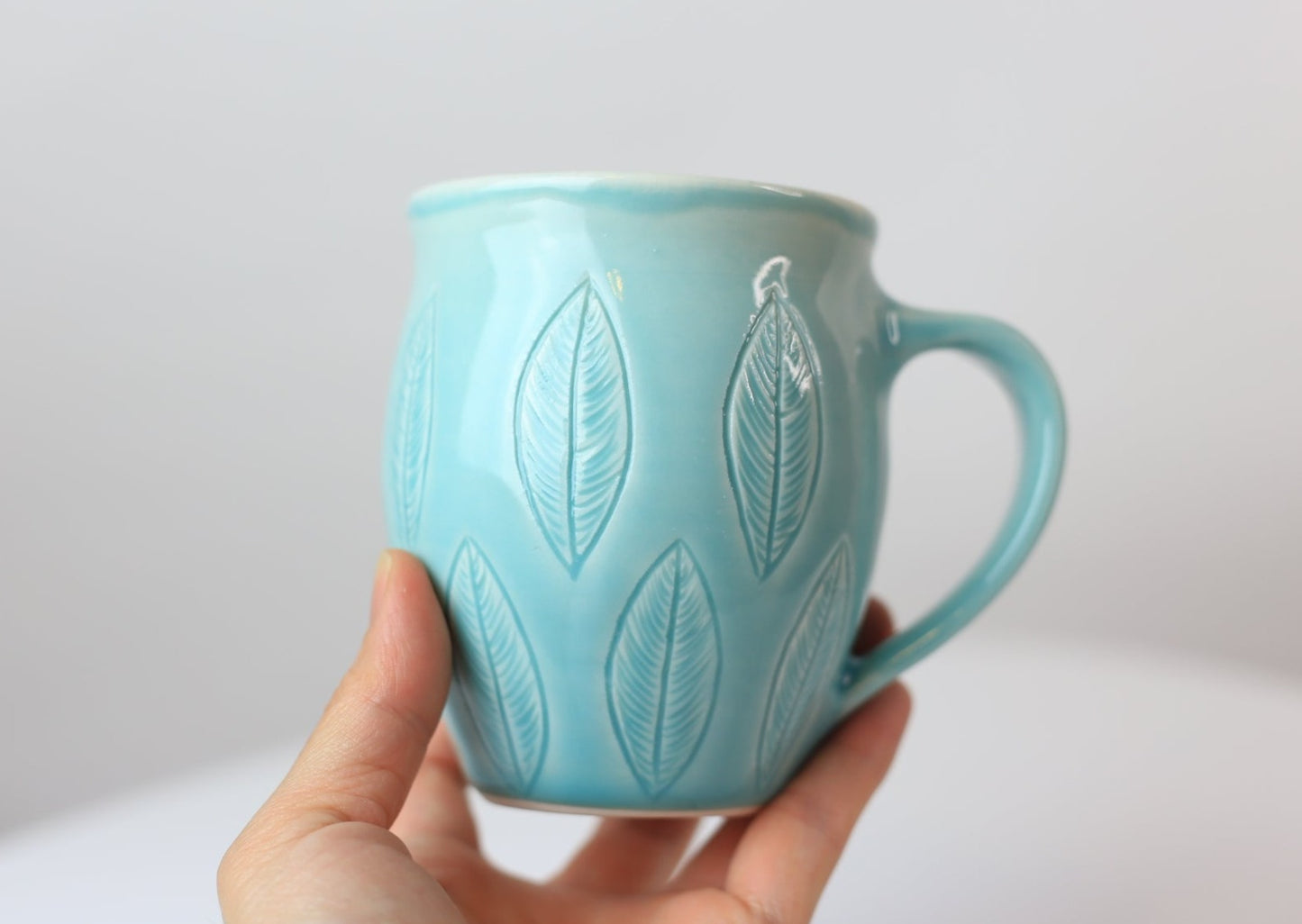 12 oz porcelain mug with carved leaves in turquoise