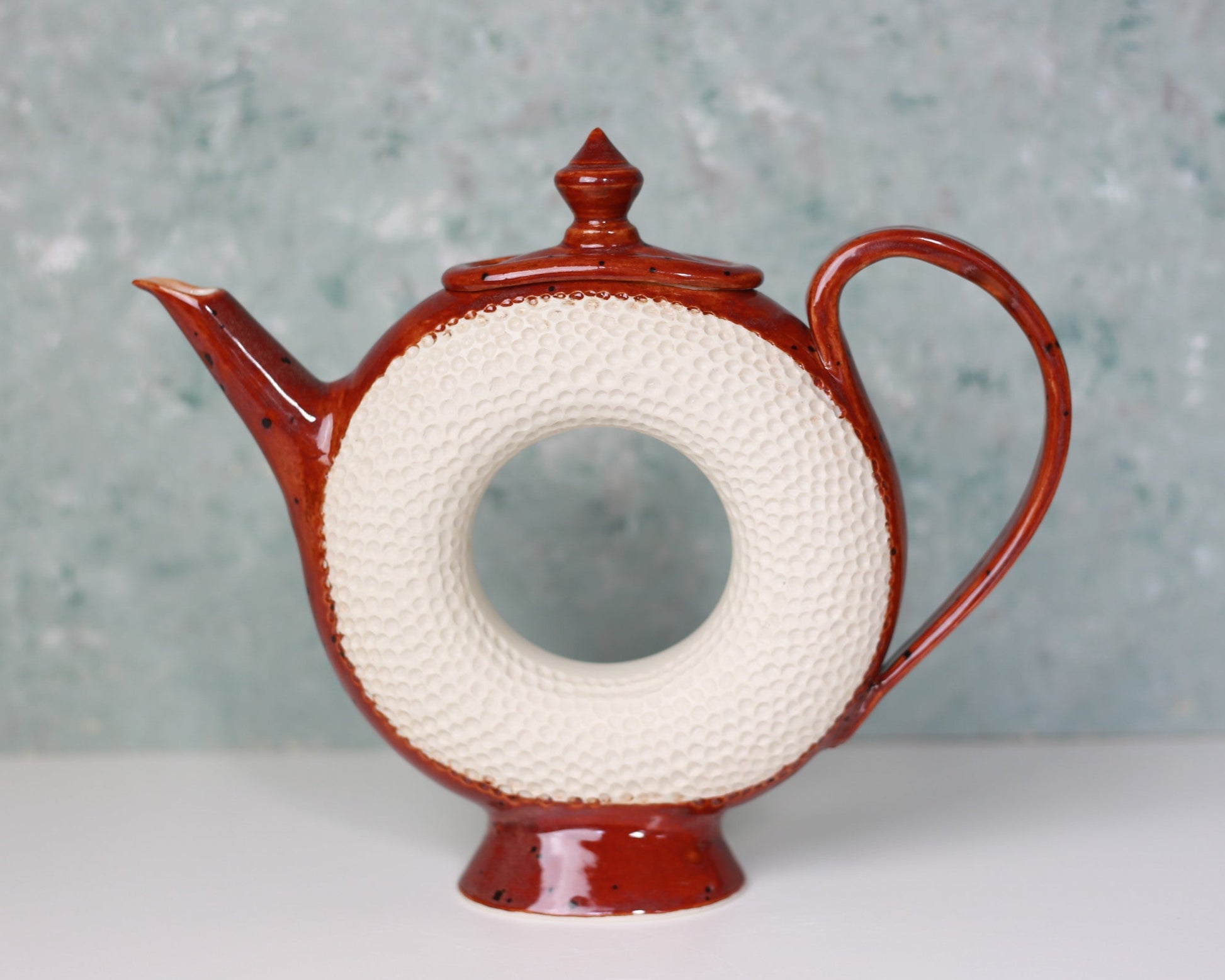 Red teapot with a white lace pattern on a gray background