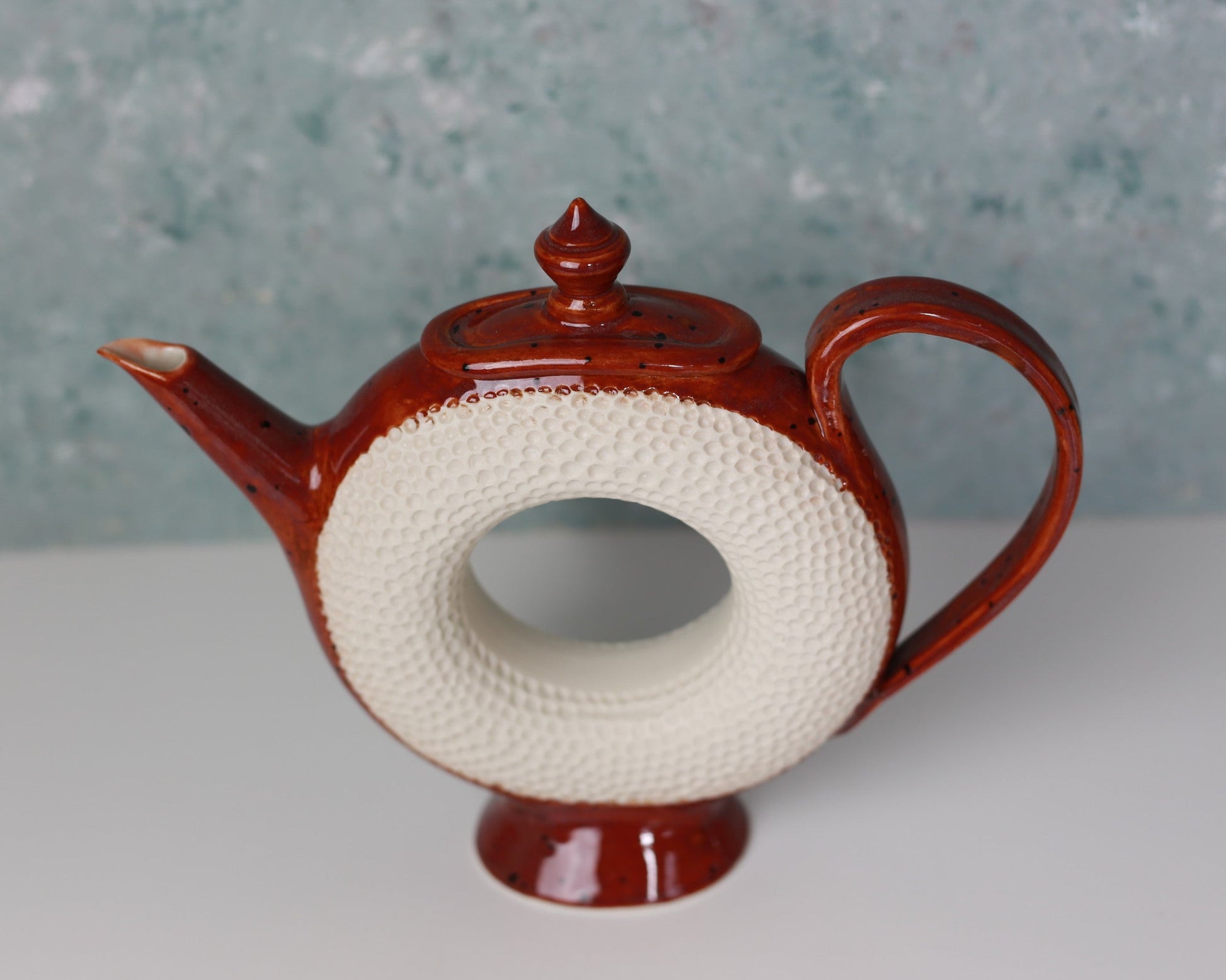 Ceramic teapot with textured white base on a light surface