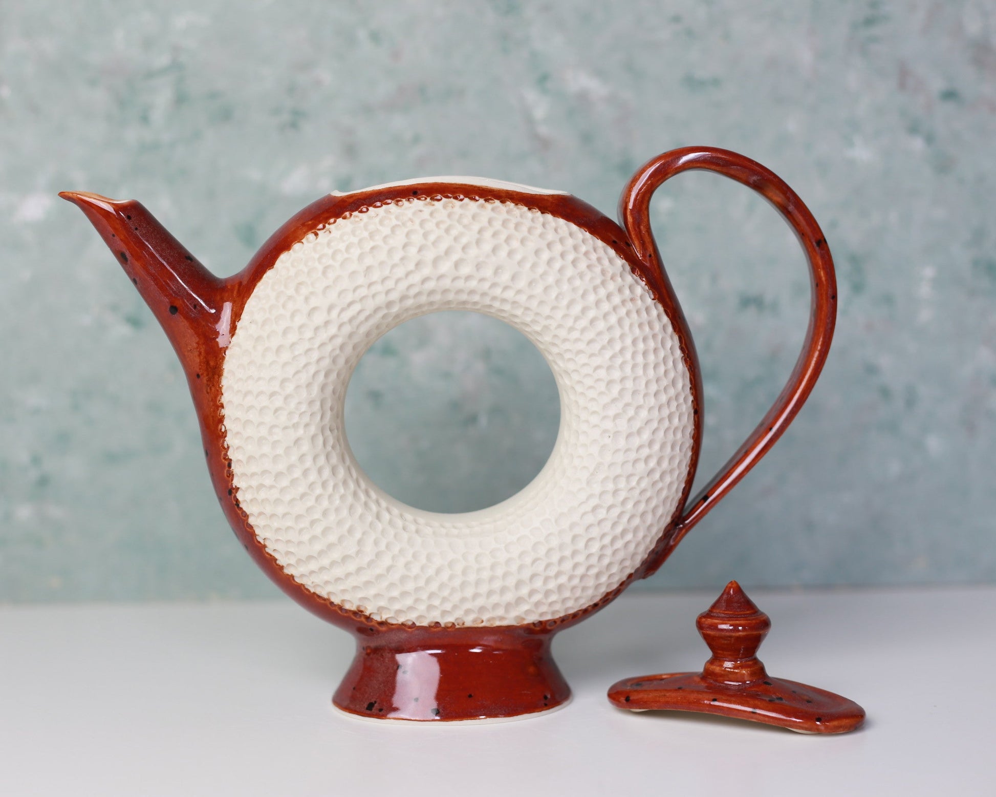 Ceramic teapot with a textured white circular design on a light gray background