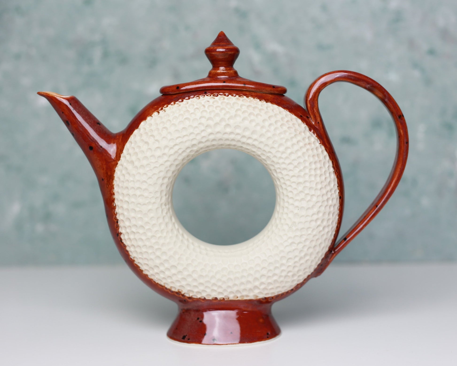 Ceramic teapot with textured white circular design on a gray background
