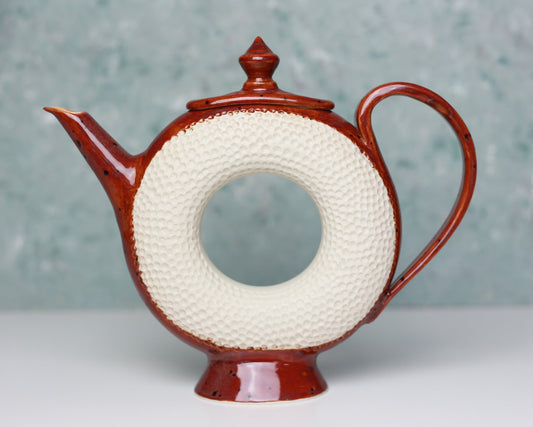 Ceramic teapot with textured white circular design on a gray background