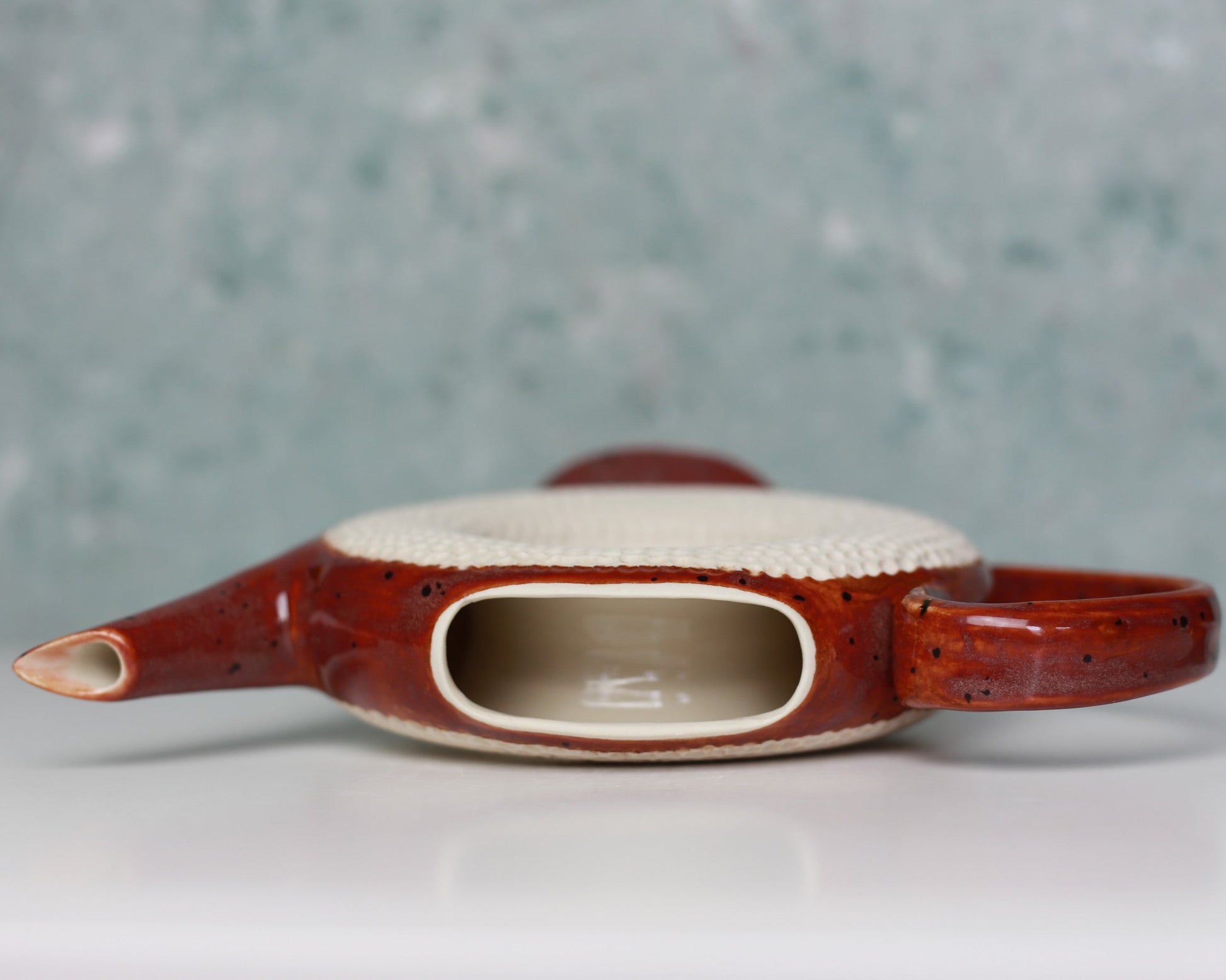 Ceramic teapot with a textured handle on a gray background