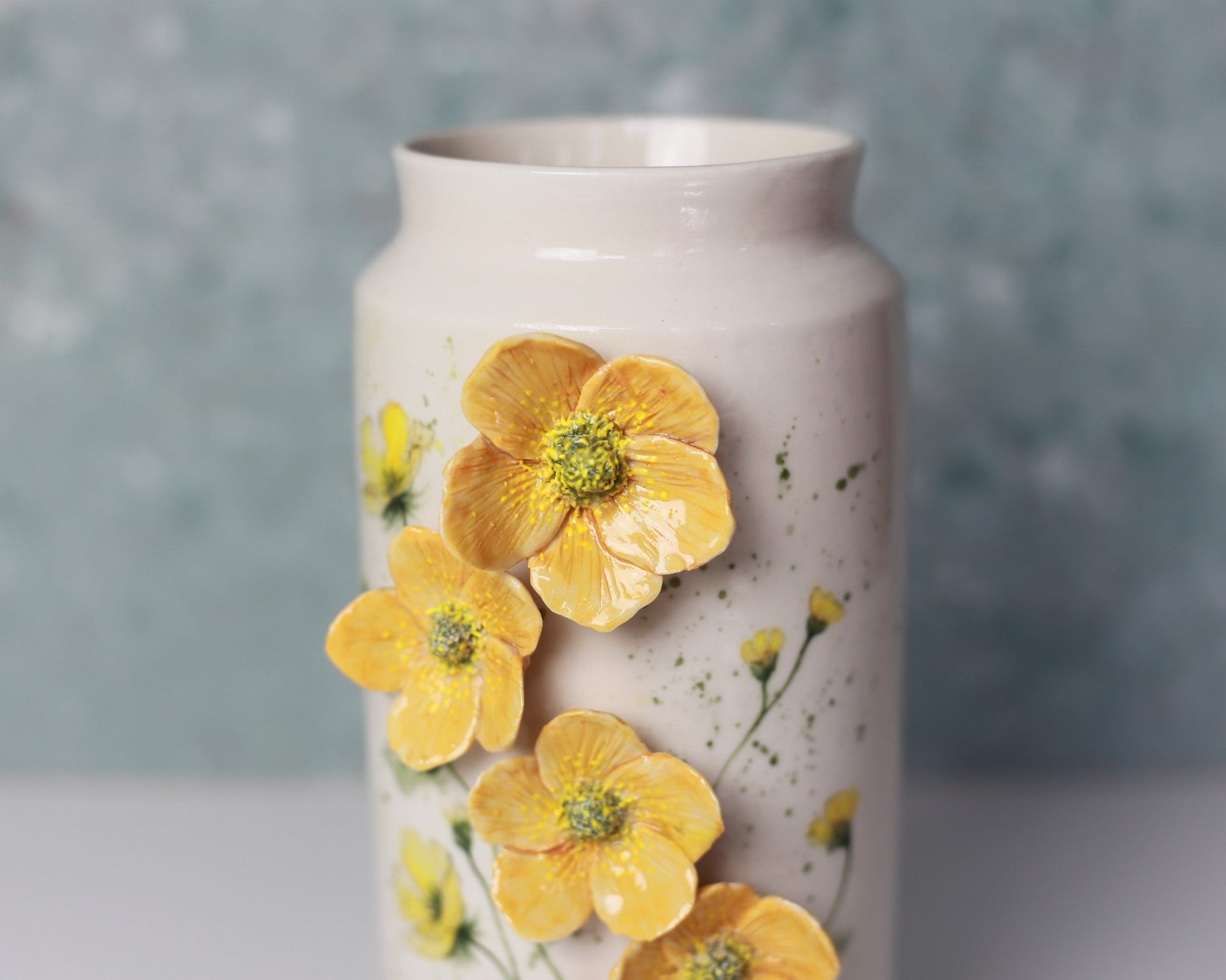 Ceramic vase with yellow floral designs on a gray background