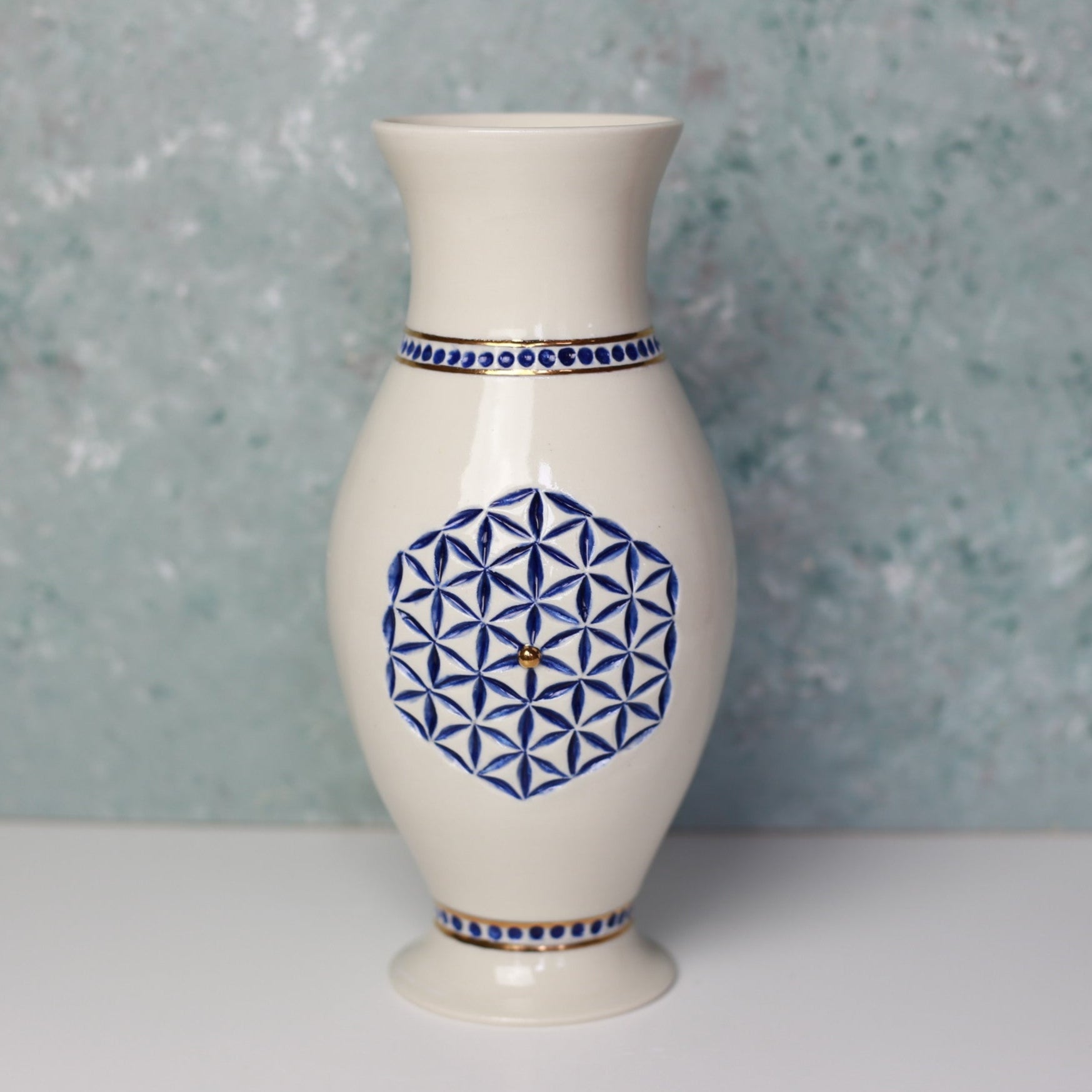 White vase with blue geometric patterns on a textured gray background