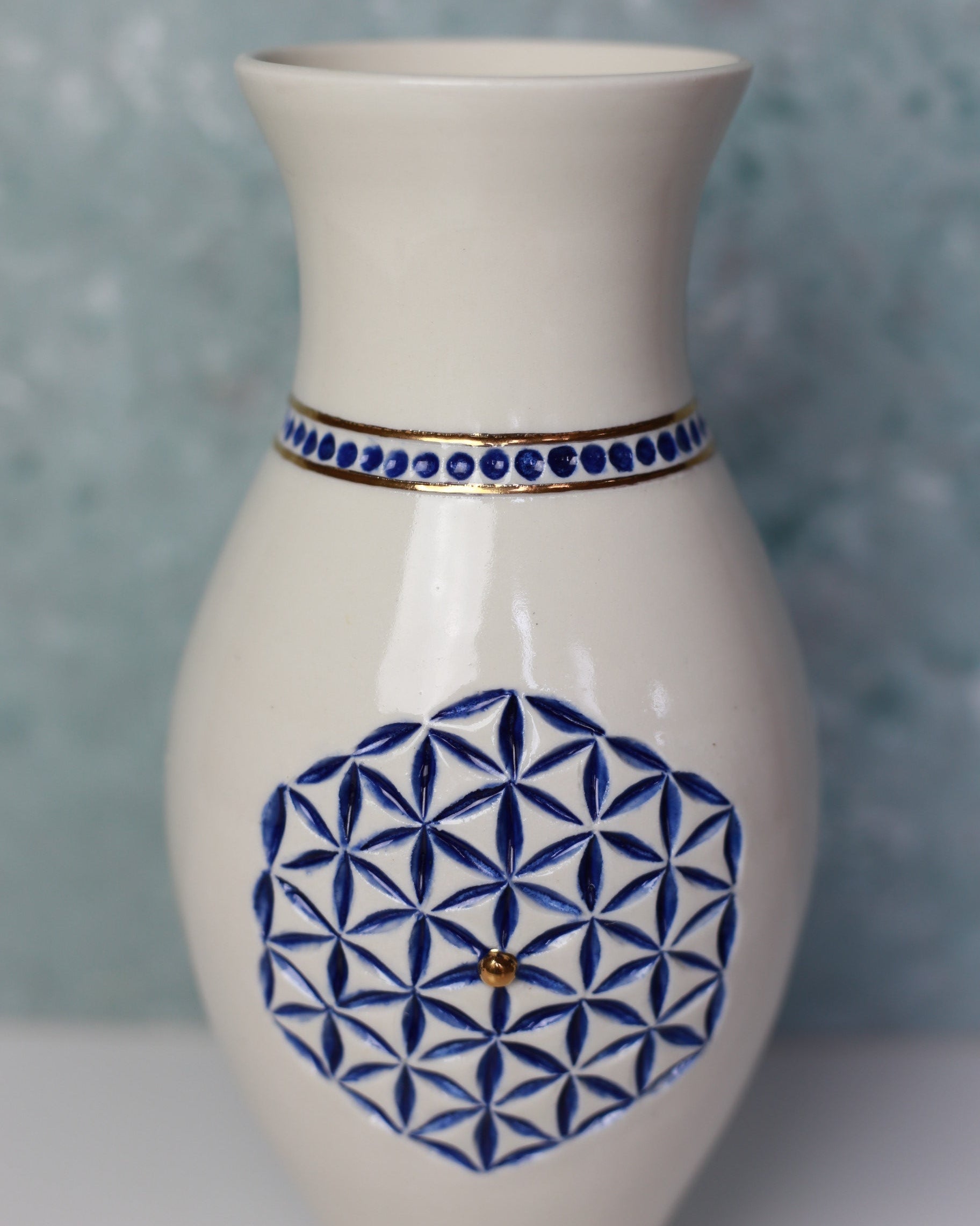 White vase with blue geometric patterns on a textured gray background