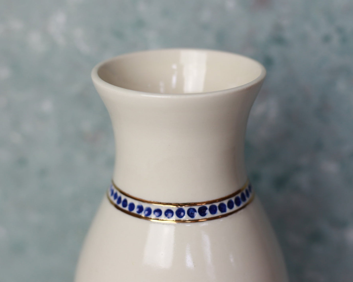 White vase with blue decorative band on a gray background