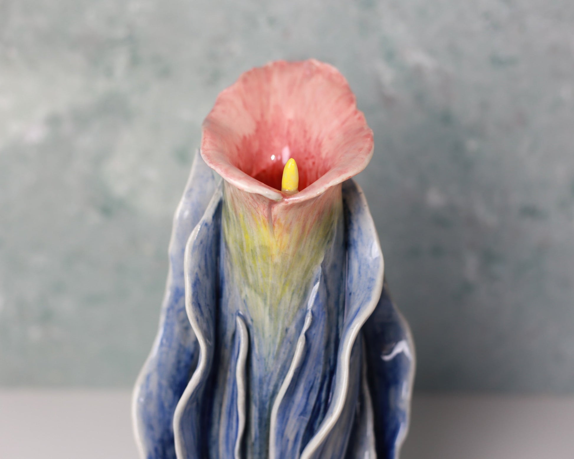 Ceramic sculpture of a flower with a textured blue base against a gray background