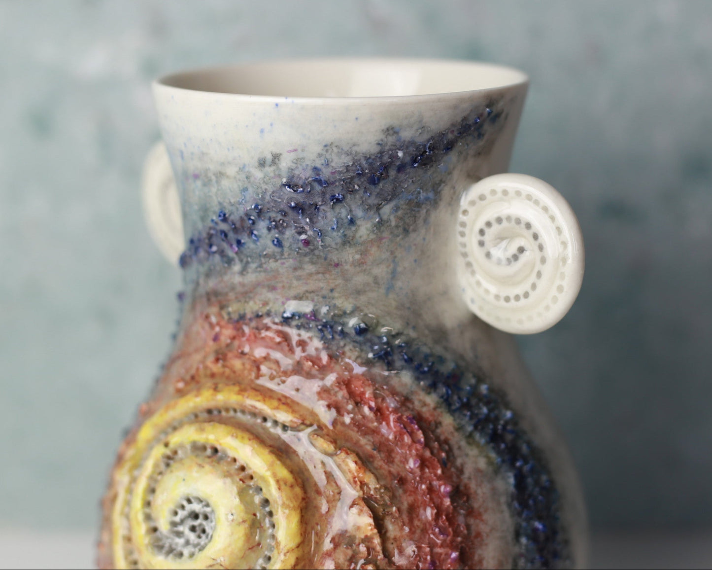 Ceramic vase with multicolored spiral design on a gray background