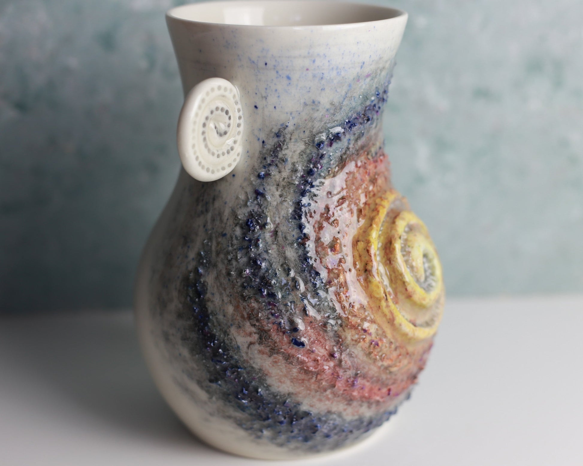 Decorative ceramic vase with multicolored glaze and circular design on a neutral background