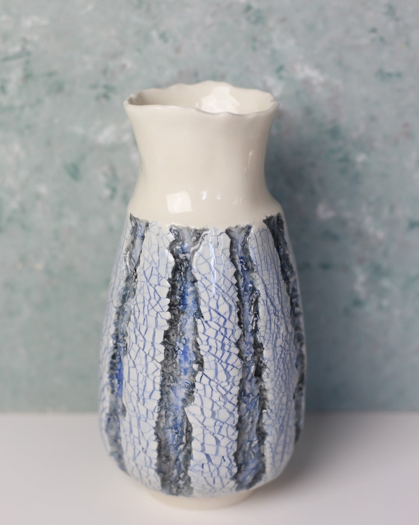 Decorative vase with a textured blue and white design on a gray background