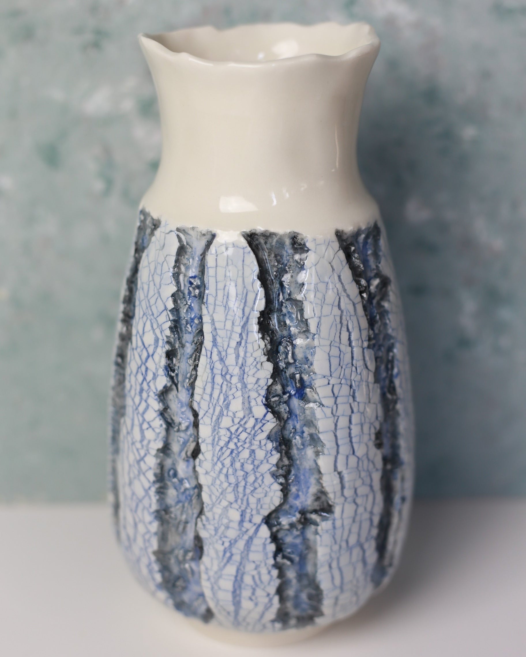 Ceramic vase with textured blue and white design on a gray background