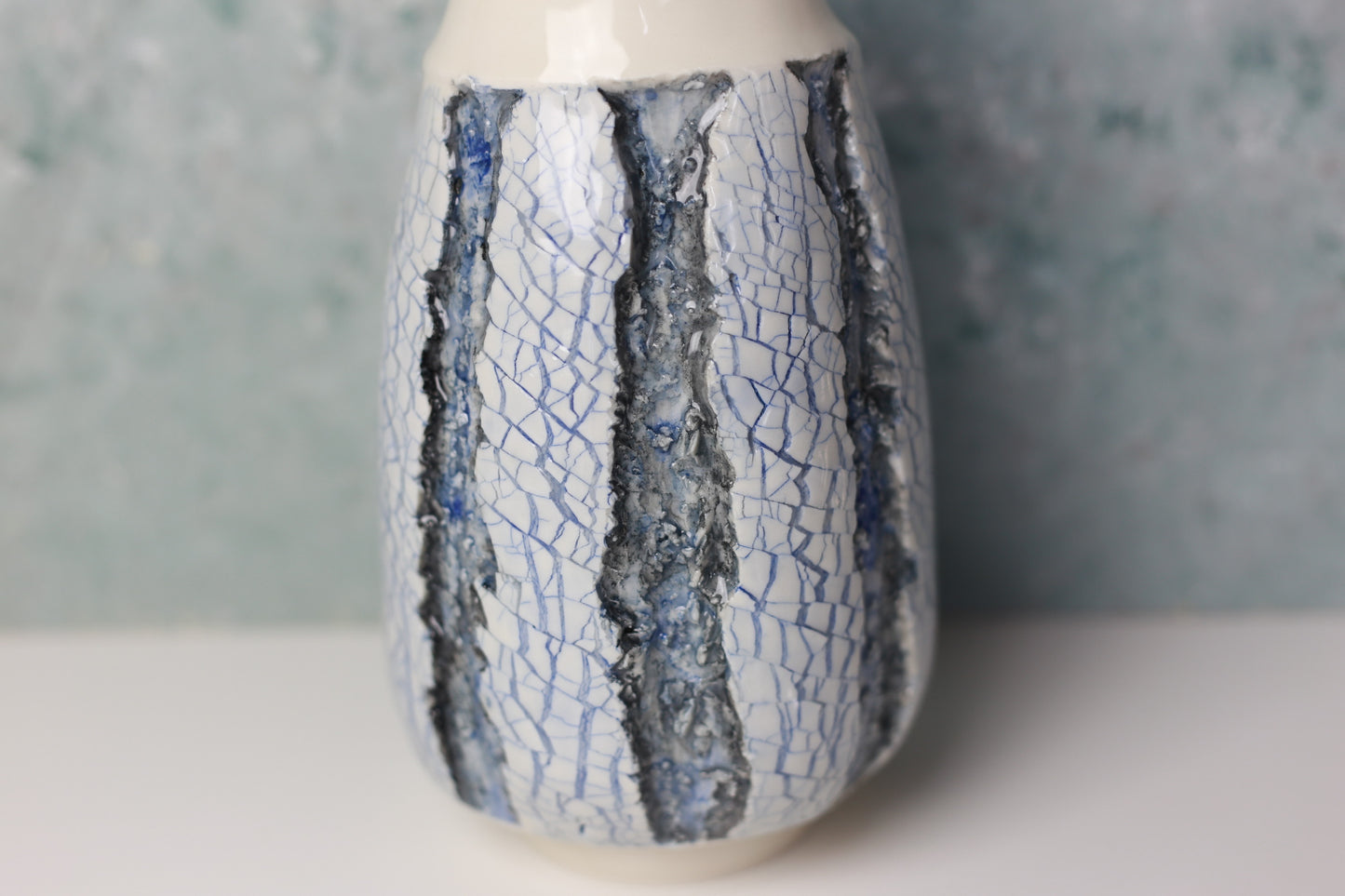 Ceramic vase with blue crackle glaze on a neutral background