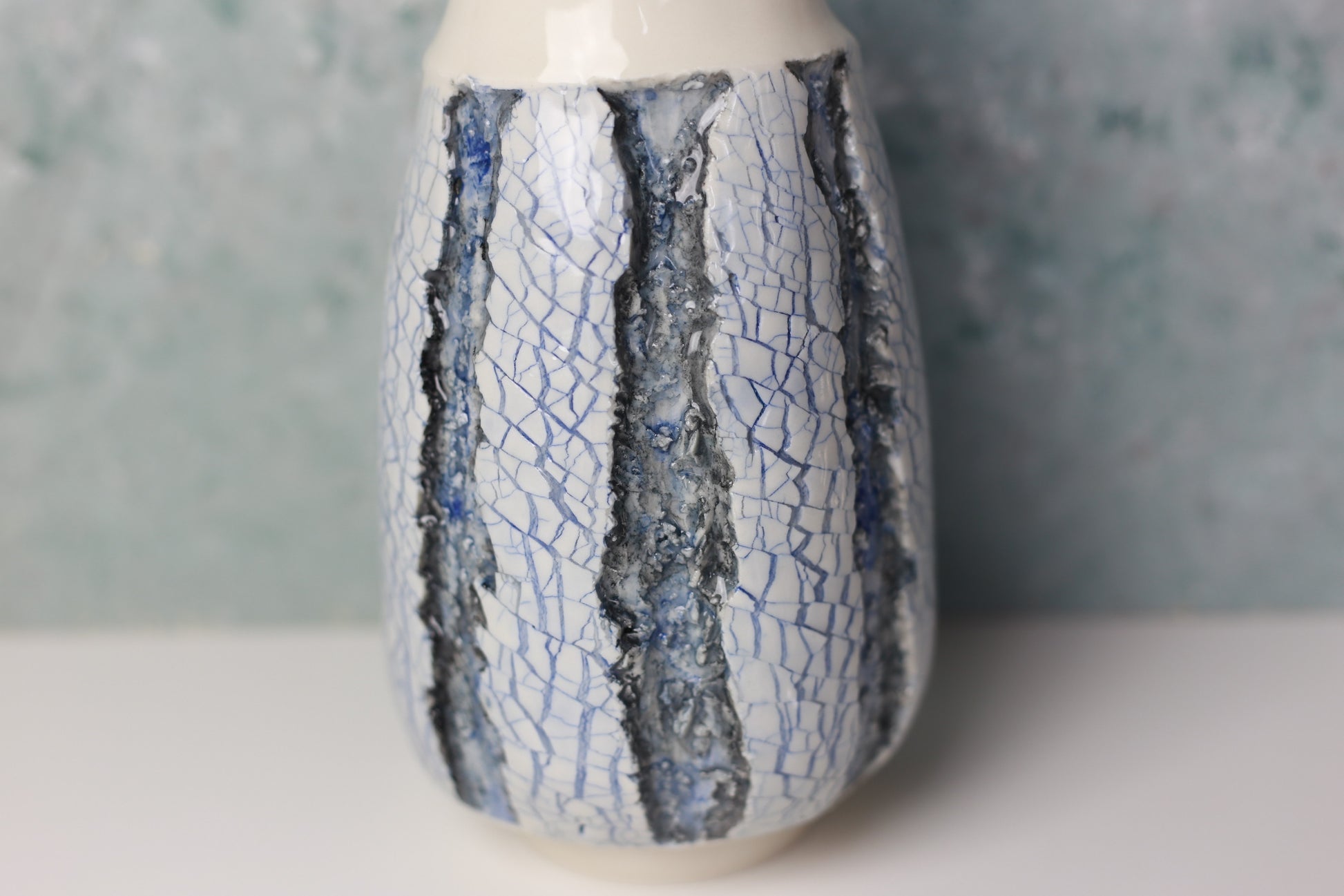 Ceramic vase with blue crackle glaze on a neutral background