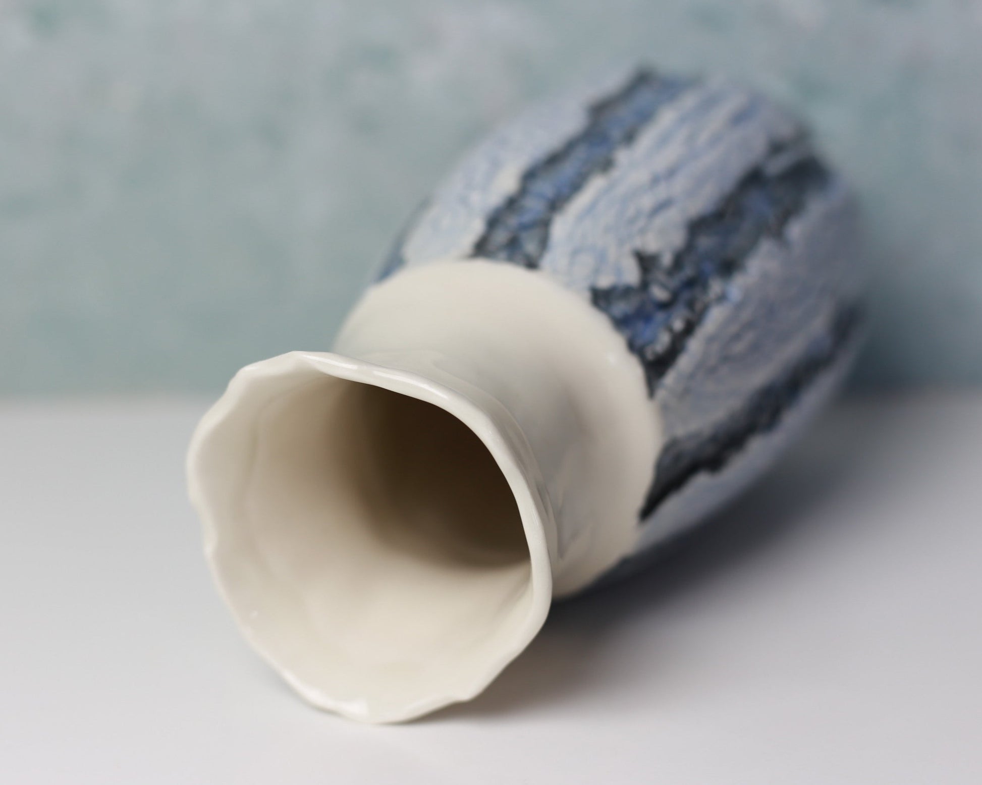 Ceramic vase with textured blue and white design on a light gray background