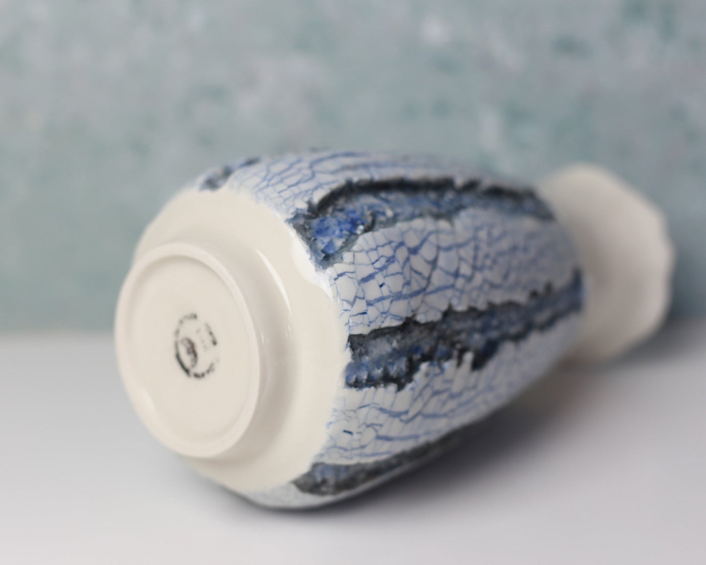 Ceramic bottle with blue crackle glaze on a gray background