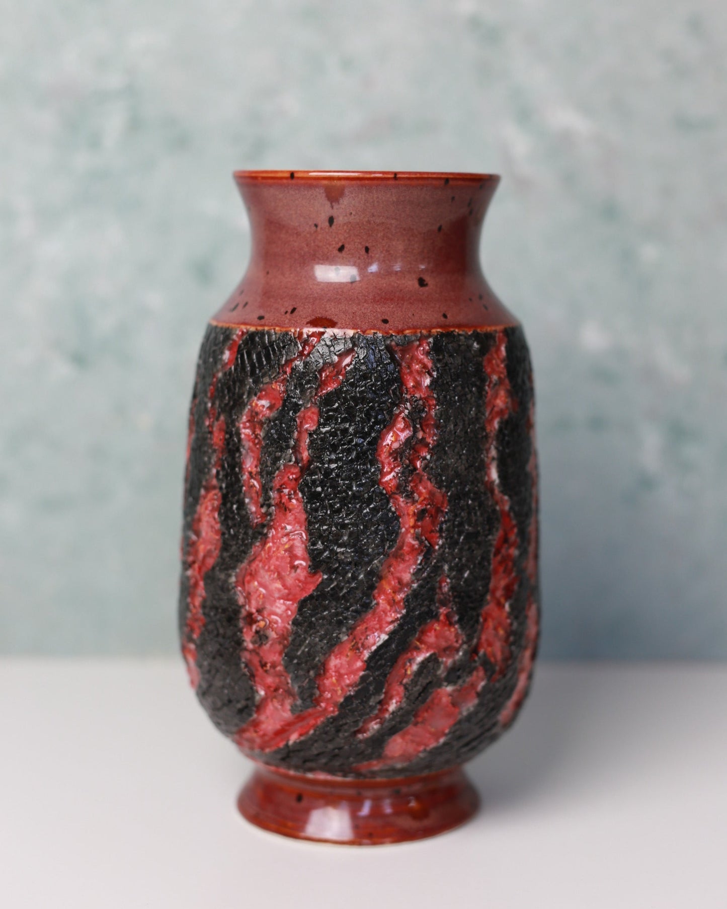 Vase with red and black marbled pattern on a light gray background