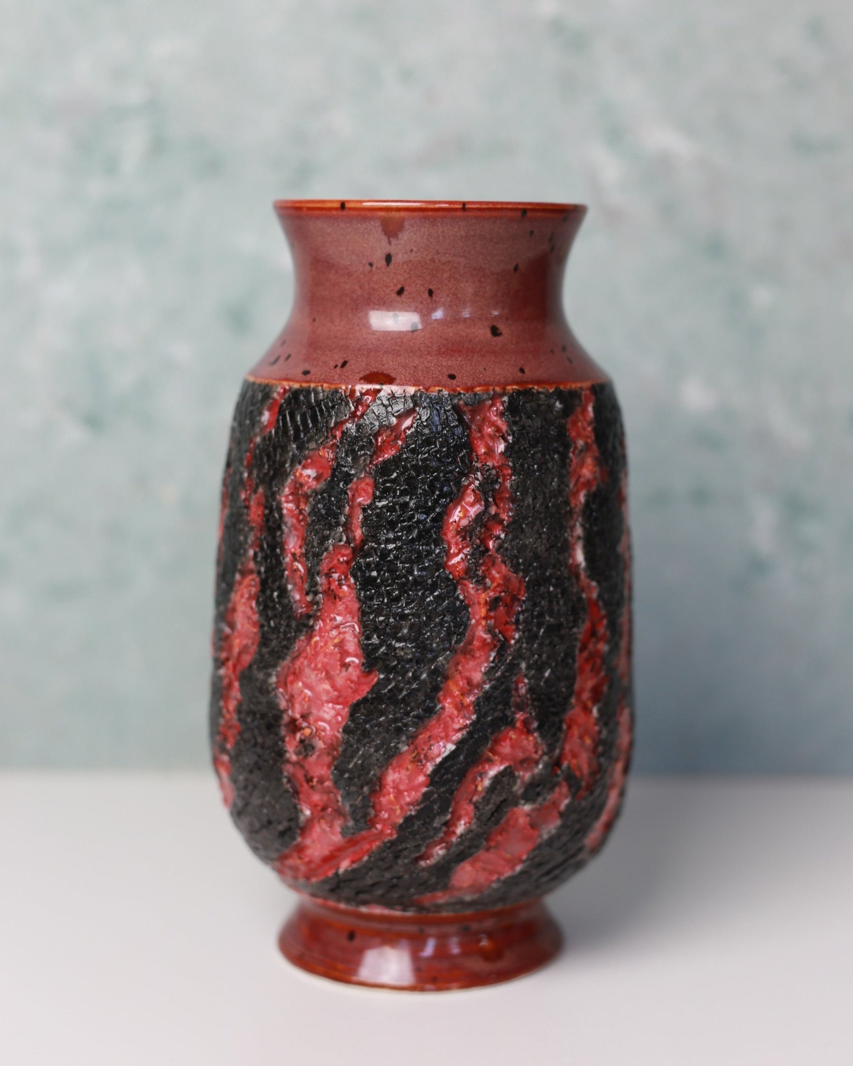 Vase with red and black marbled pattern on a light gray background