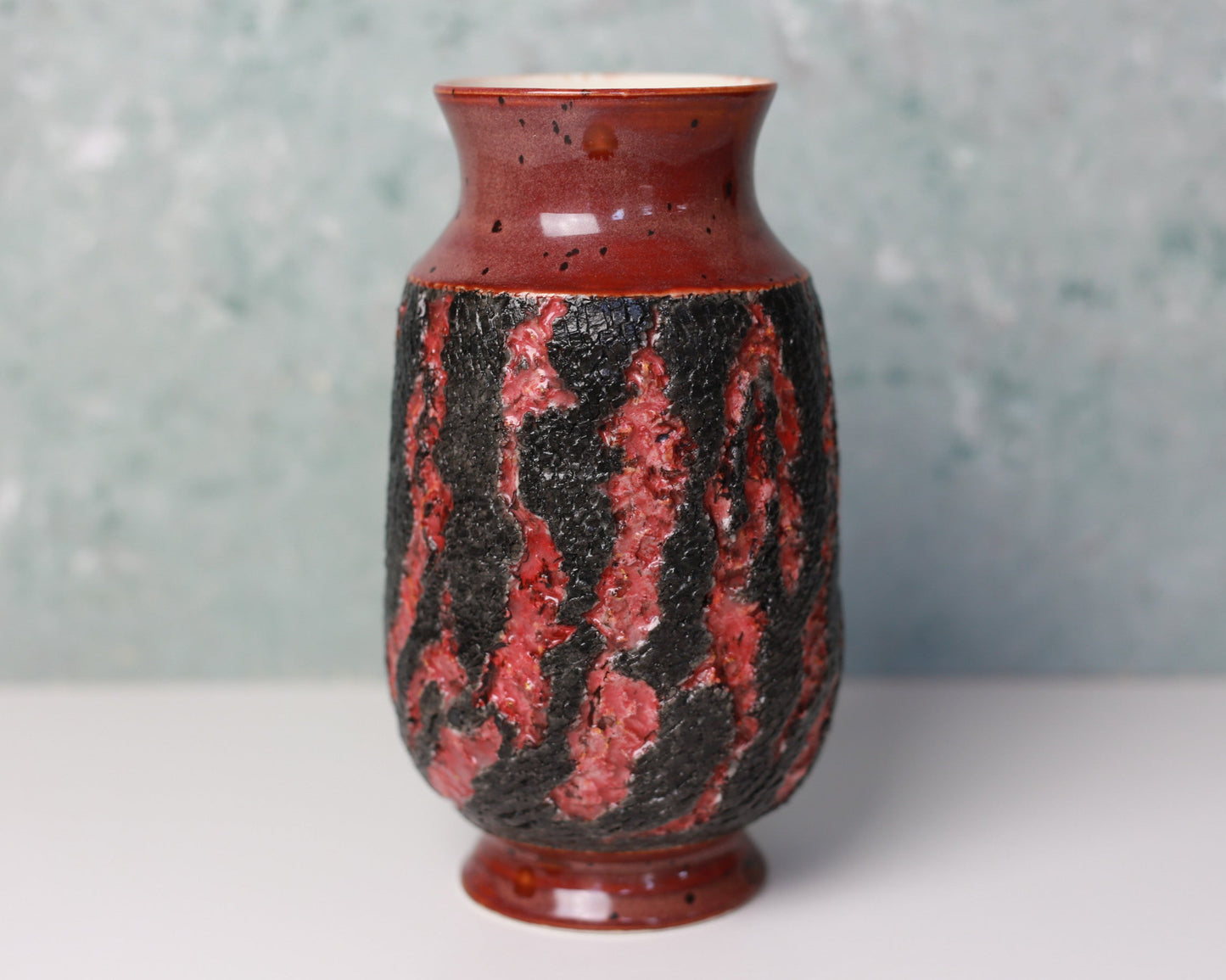 Ceramic vase with red and black pattern on a gray background