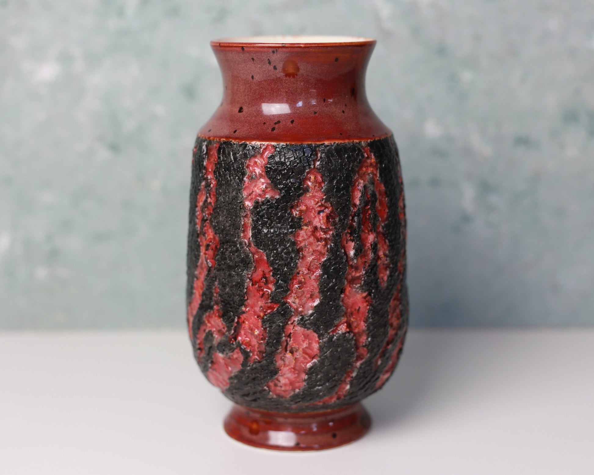 Ceramic vase with red and black pattern on a gray background