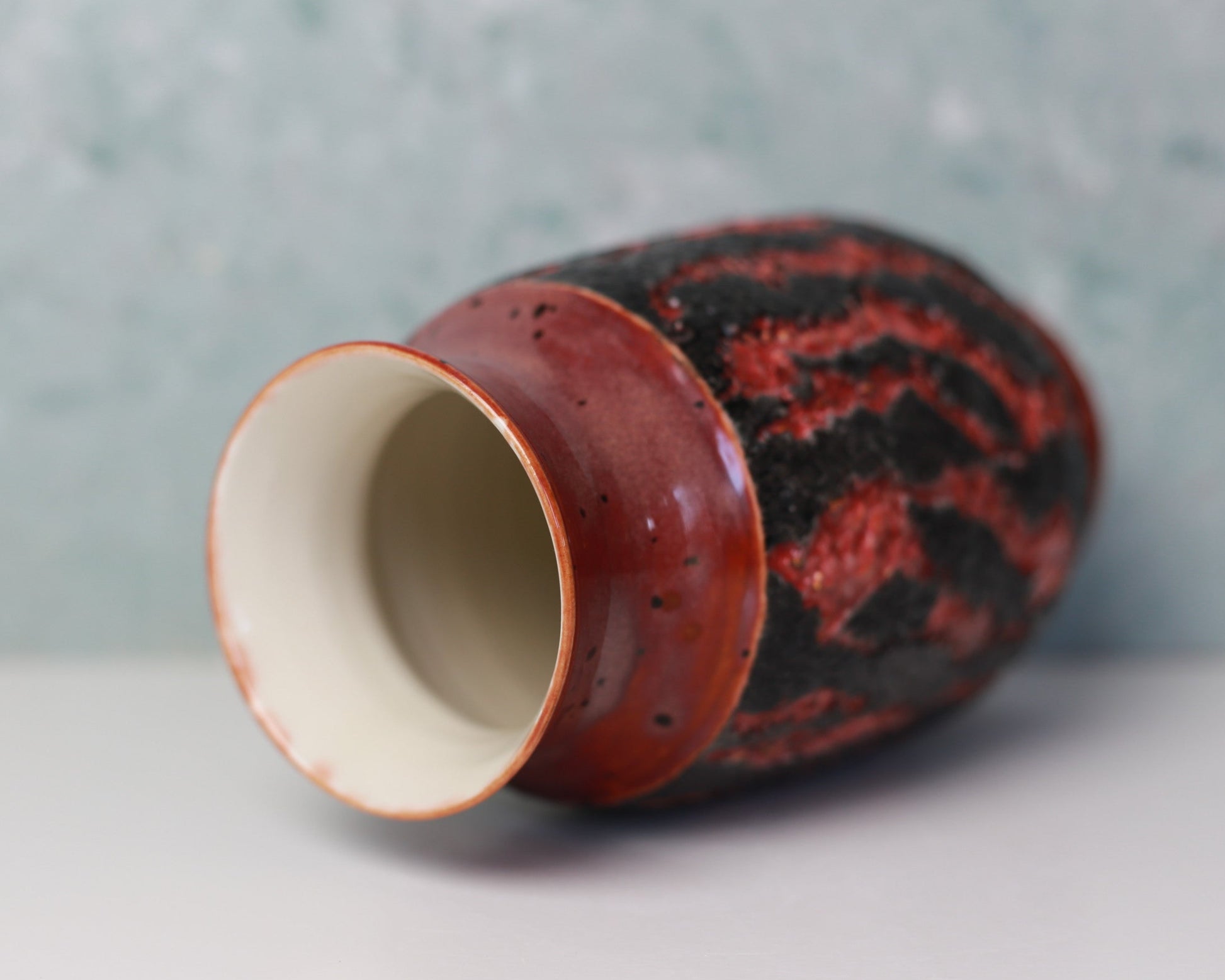 Ceramic vase with red and black pattern on a gray background