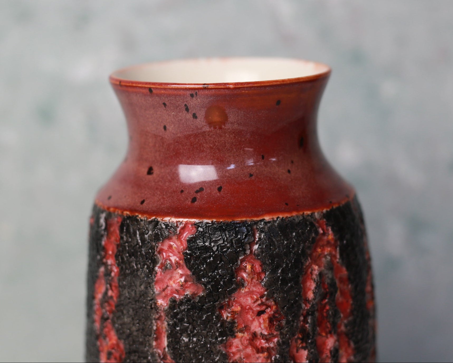 Ceramic vase with red and black glaze on a gray background