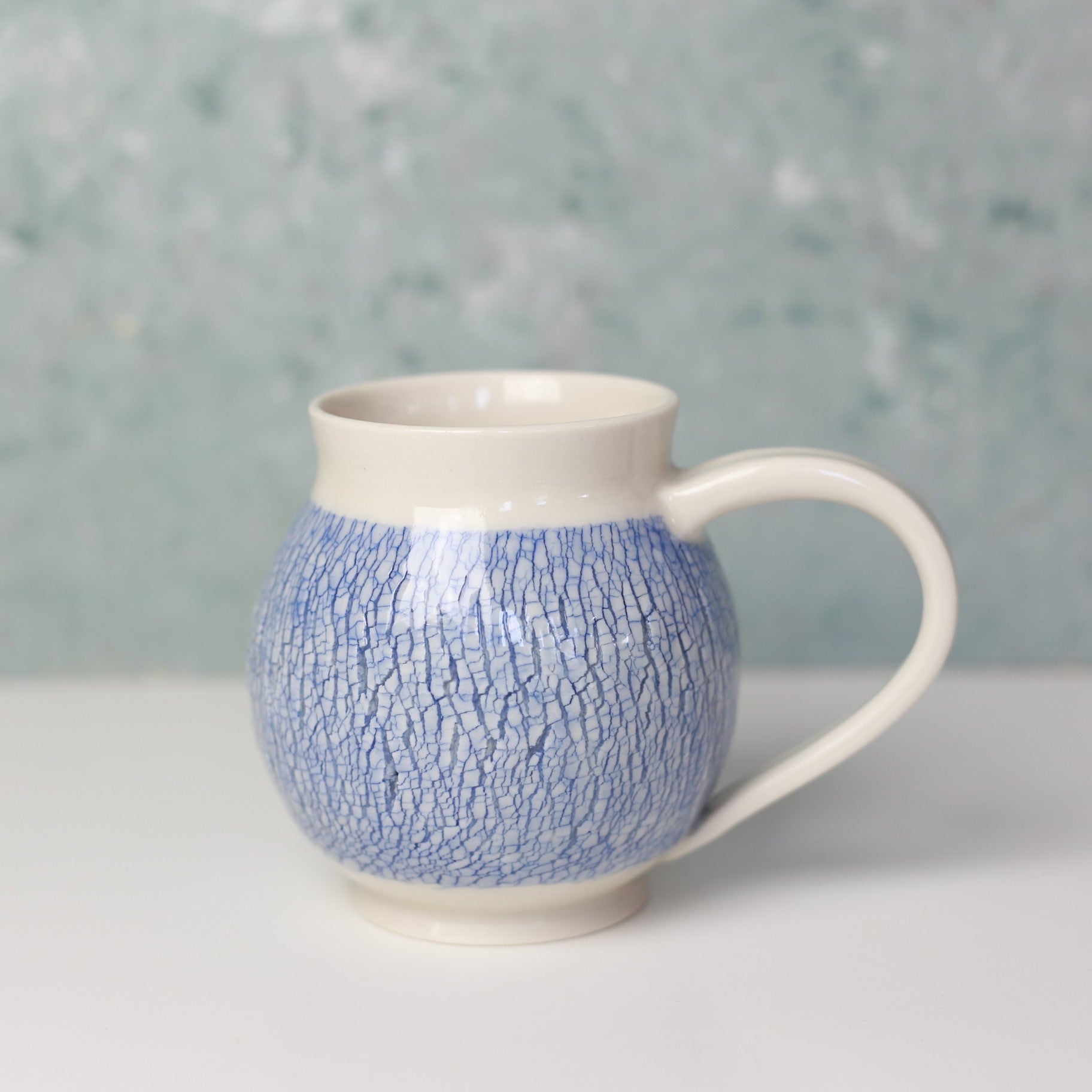 Ceramic mug with blue textured pattern on a light gray background