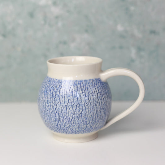 Ceramic mug with blue textured pattern on a light gray background