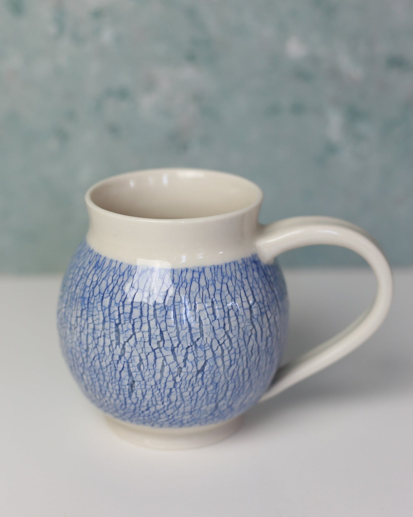 Ceramic mug with textured blue and white design on a neutral background
