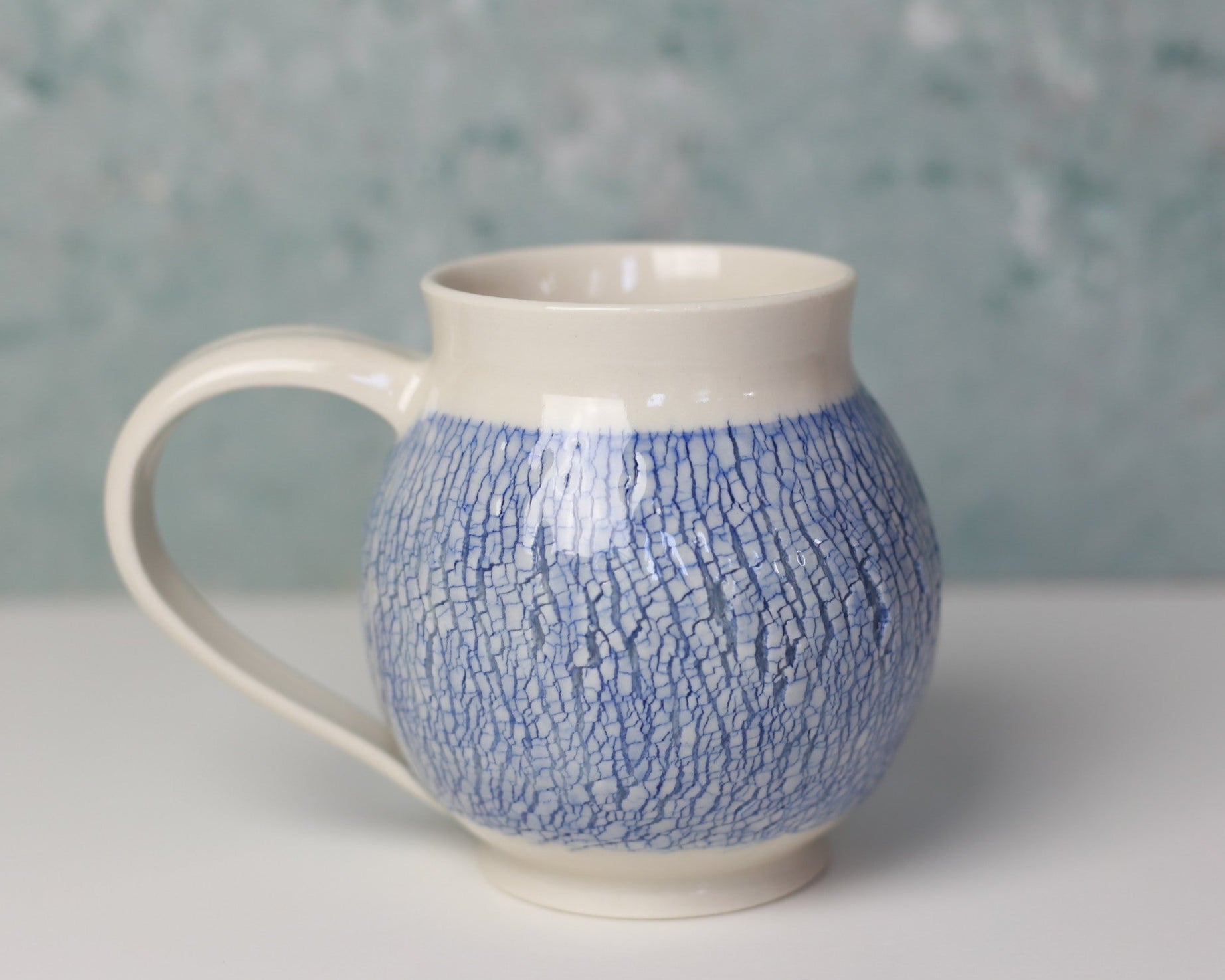 Ceramic mug with blue textured pattern on a gray background