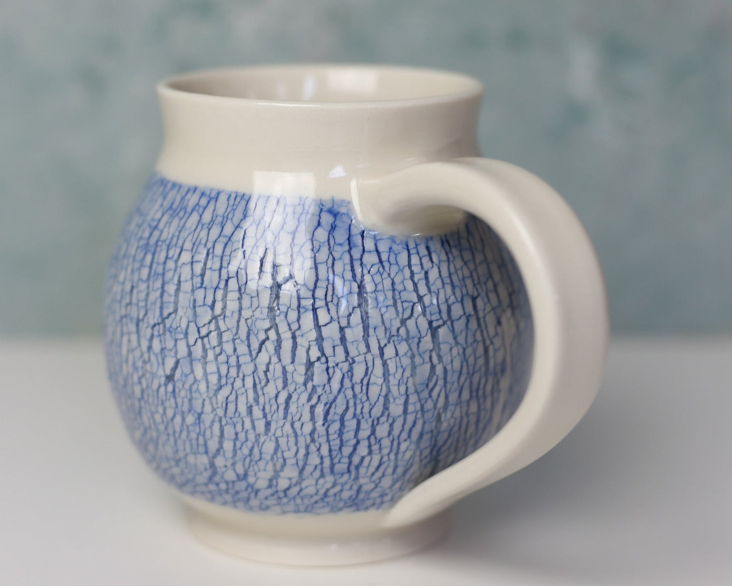 Ceramic mug with blue textured pattern on a light gray background