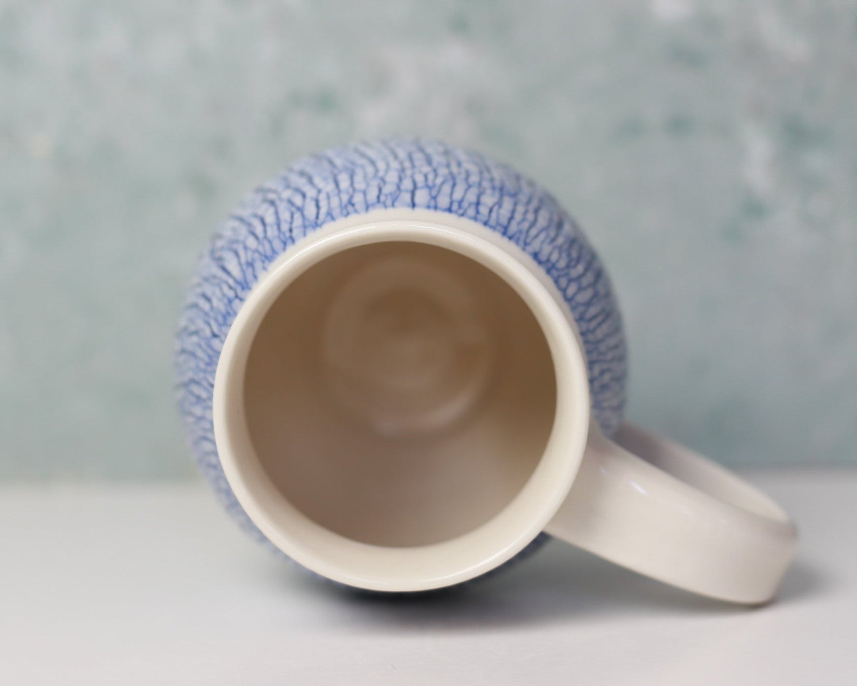 Ceramic mug with textured blue exterior on a light gray background