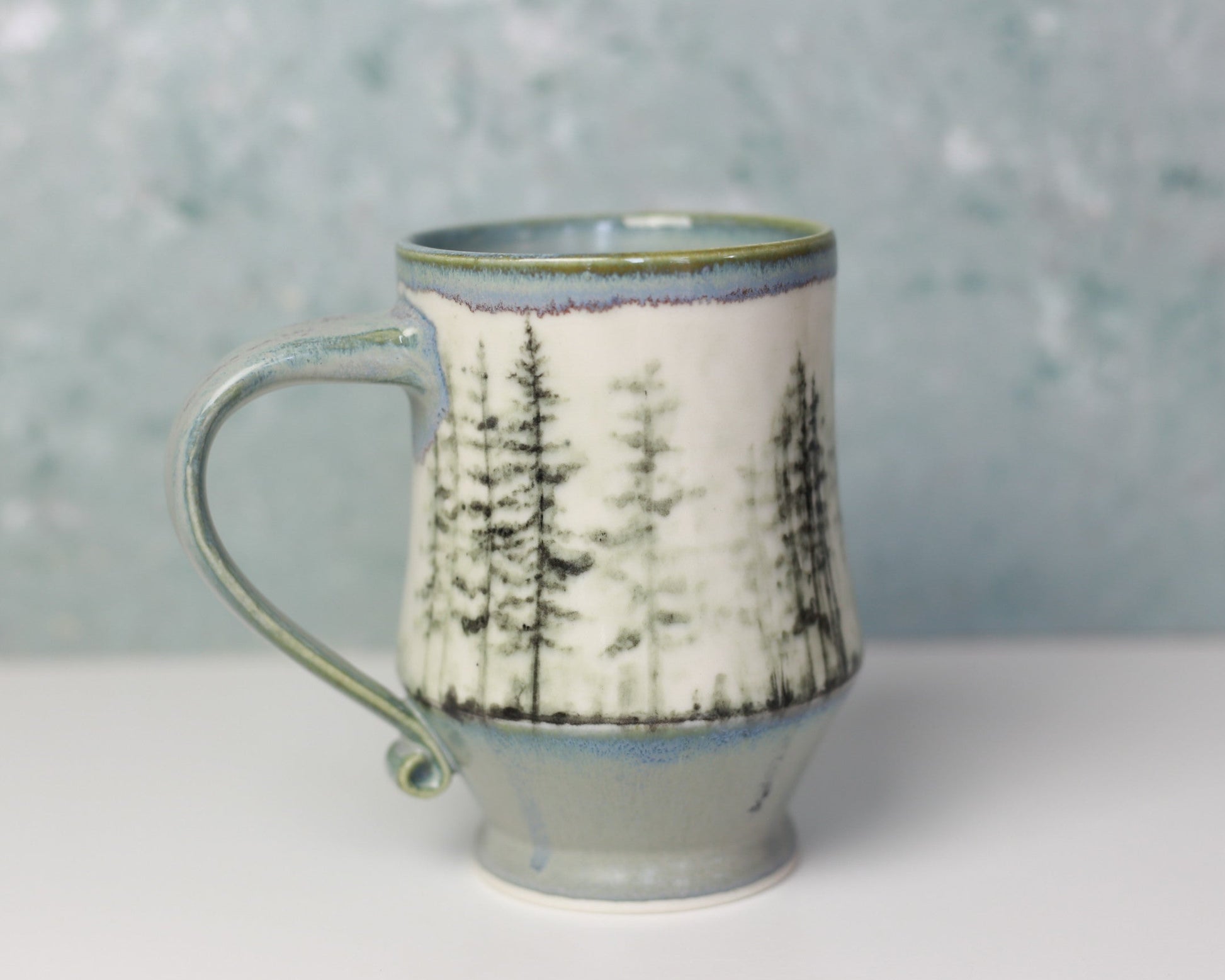 Ceramic mug with tree pattern on a white surface and gray background