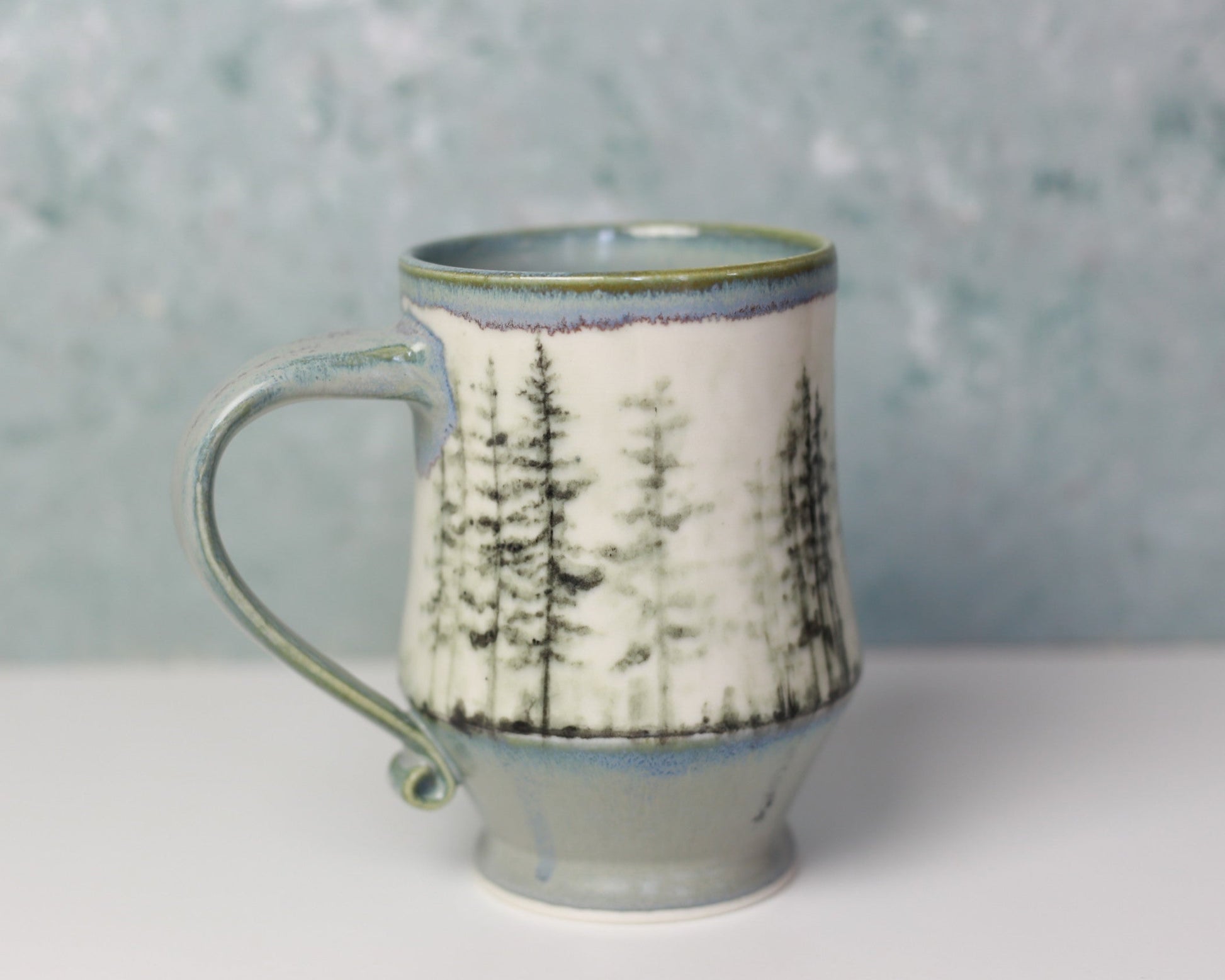 Ceramic mug with a forest design on a gray background