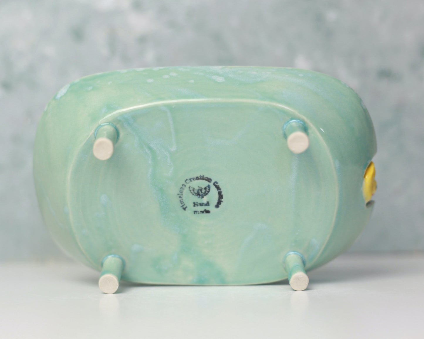 Small ceramic bathtub soap dish with a yellow duck on a light gray background