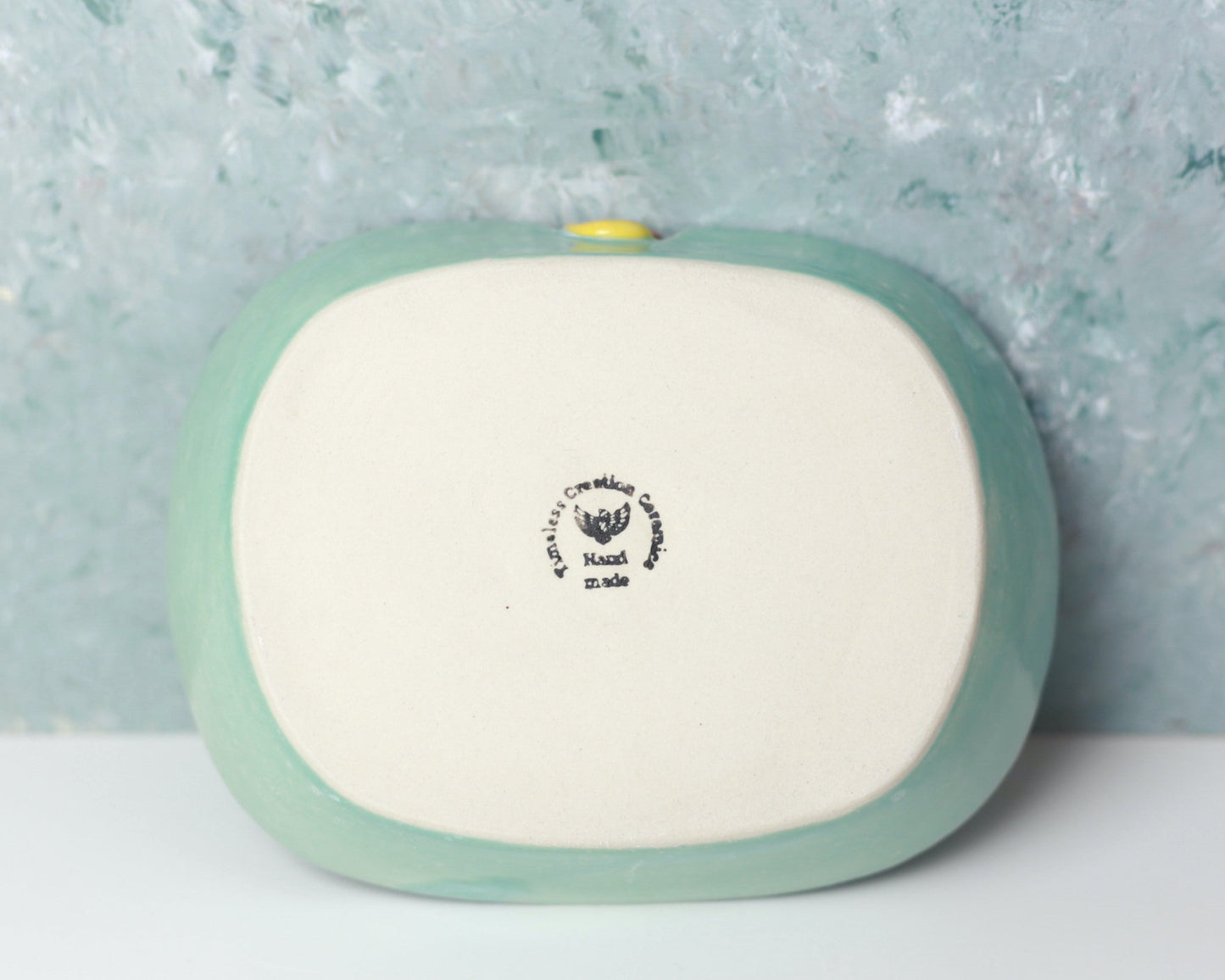 Green ceramic soap dish with a yellow rubber duck on a light gray background