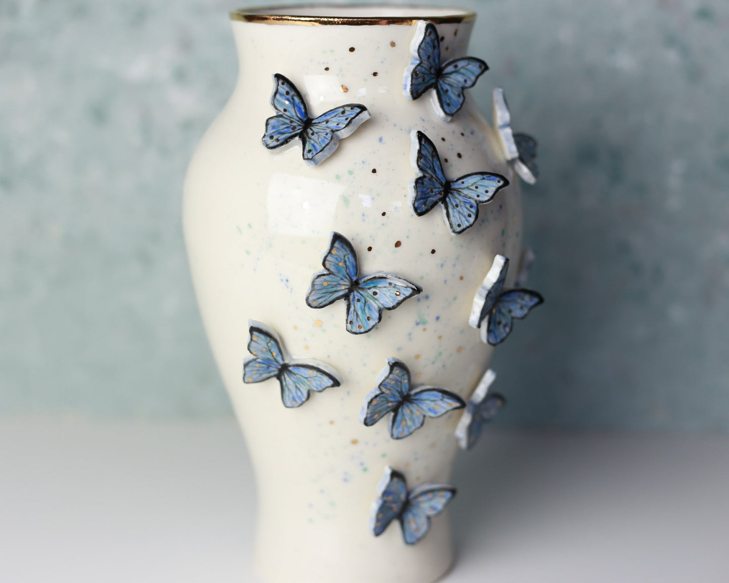 White ceramic vase with blue butterfly decorations on a light background