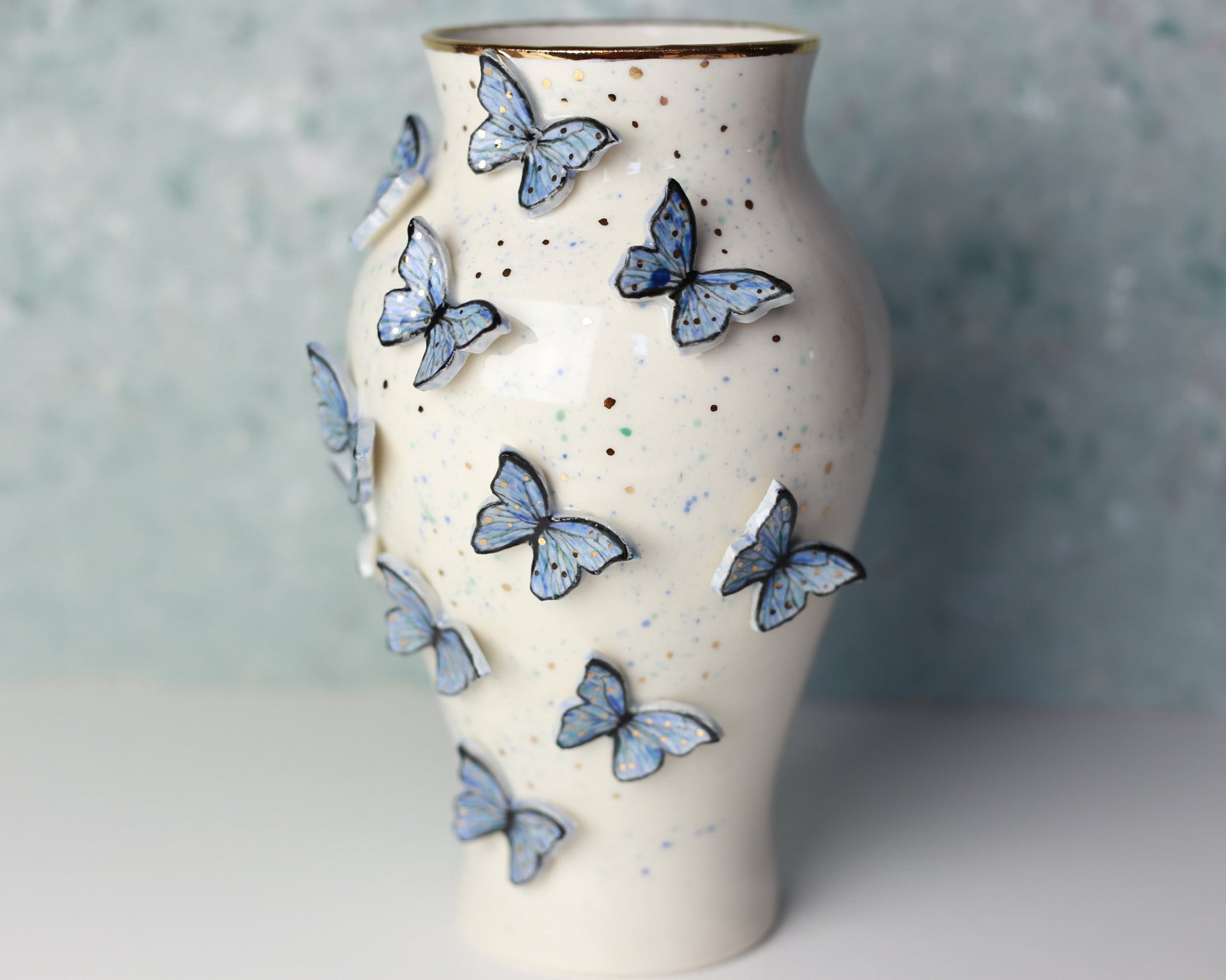 Ceramic vase with blue butterfly decorations on a neutral background