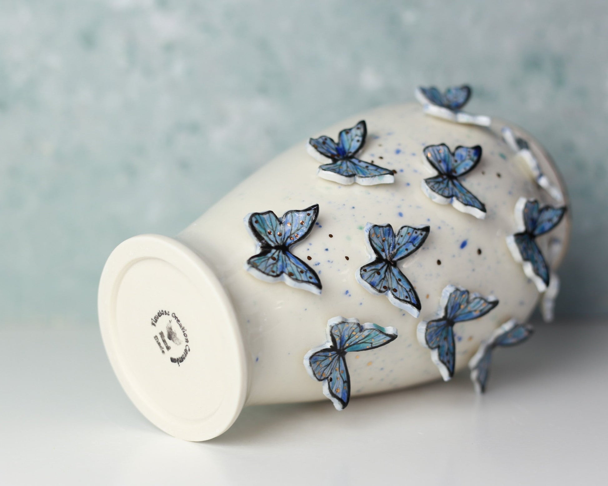 Ceramic vase with blue butterfly decorations on a light gray background